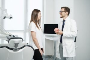 Dentist and patient standing in treatment room, engaged in conversation